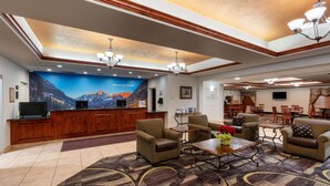 A lobby with a reception desk, seating area, and a large mural of mountains. - La Quinta Inn & Suites by Wyndham Rifle (Rifle)