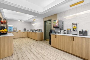 Una cocina moderna con armarios de madera, un refrigerador, una cafetera y una cesta de fruta.