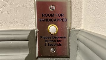 Señal en la pared que indica una habitación para personas con discapacidad, con un botón que se presiona durante cinco segundos.