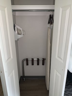 A walk-in closet with a hanging rack, a shelf with a hairdryer, and a towel rack.