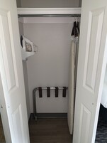 Un vestidor con una percha, un estante con secador de pelo y un perchero.