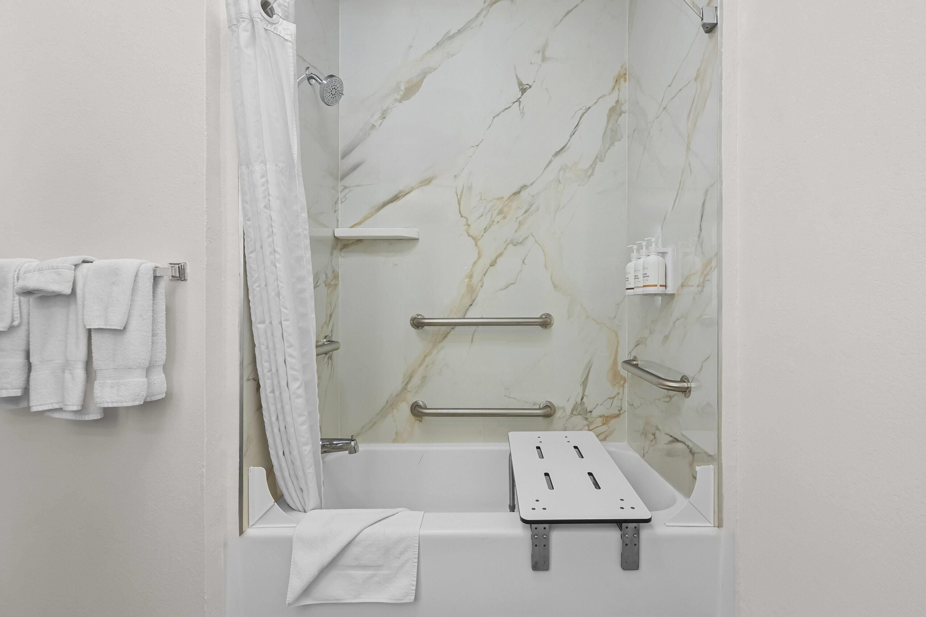 A bathroom with a bathtub, a shower, marble walls, and a towel rack.