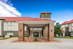 A hotel with a red-tiled roof, a covered entrance, and a sign with a sun logo. - La Quinta Inn & Suites by Wyndham Rifle (Rifle)