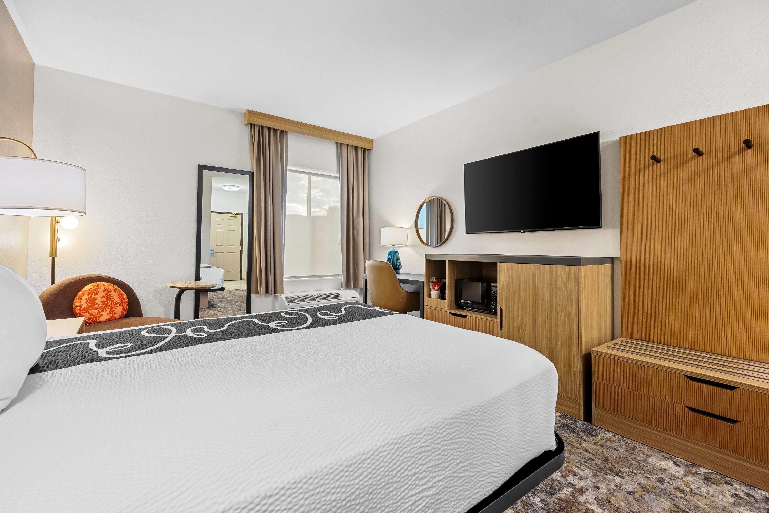 Una habitación de hotel con una cama, televisión, escritorio y silla.
