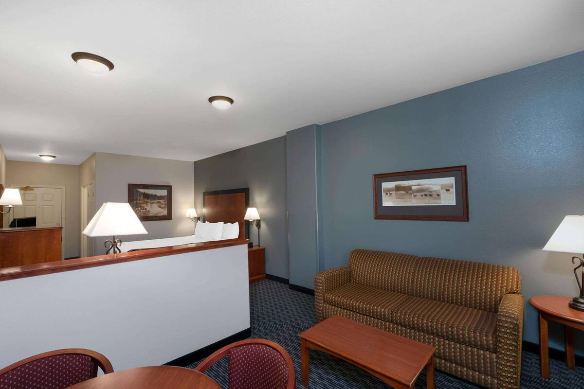 A hotel room with a reception desk, a sofa, a small table, and a chair.