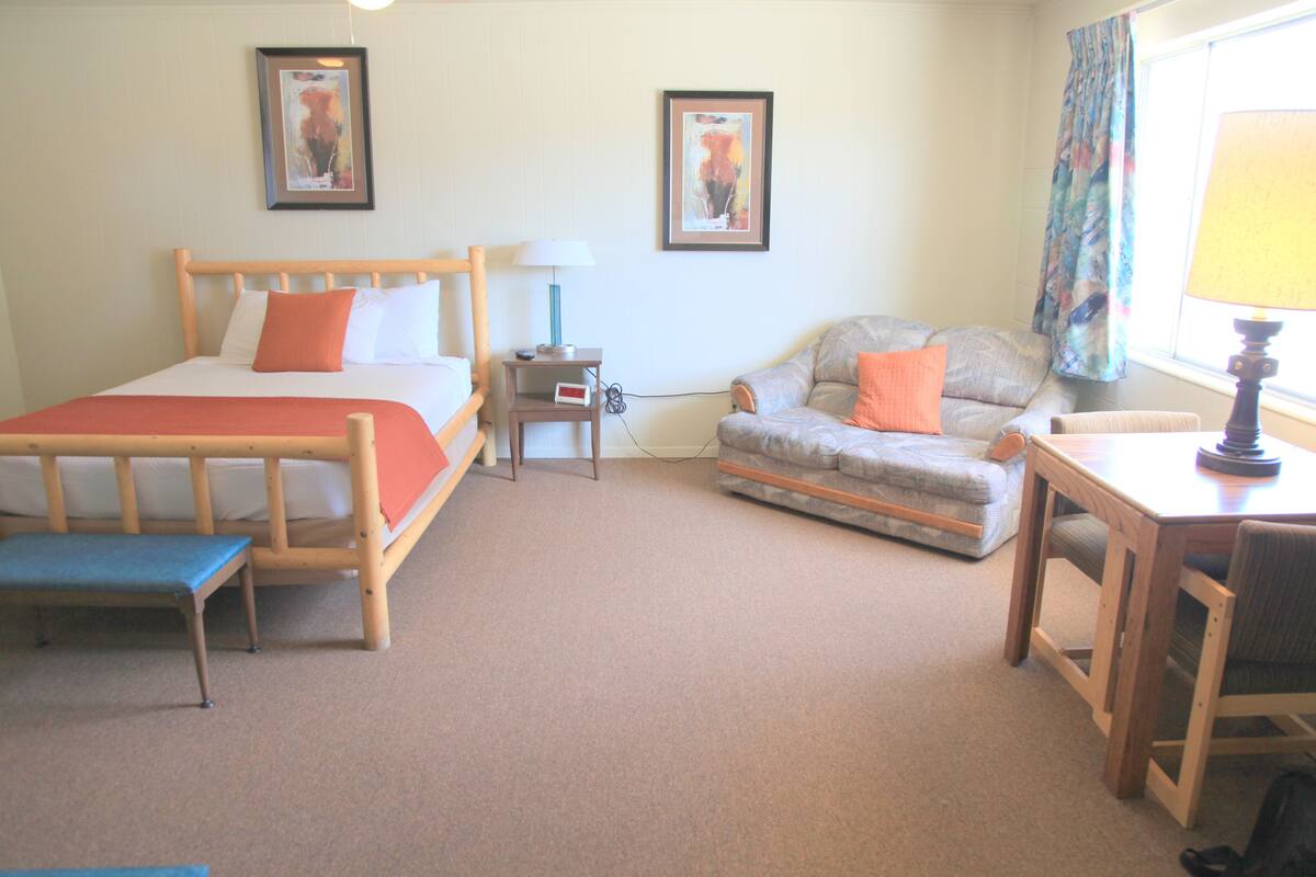 A hotel room with a bed, a sofa, a small table, and a desk.