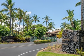 A stone wall with a sign for Hilton Grand Vacations Club at Waikoloa Beach Resort.