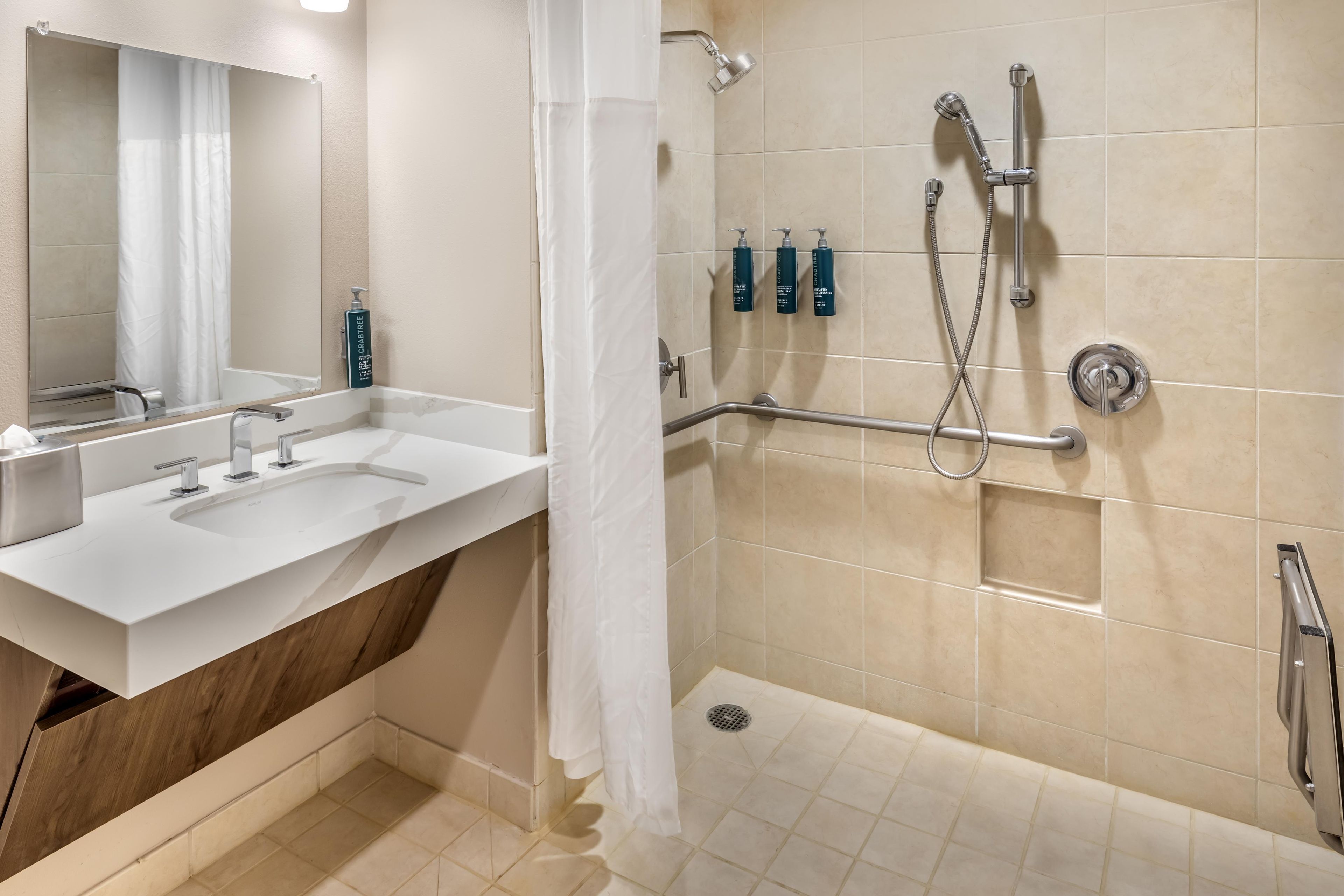 Une salle de bain avec deux lavabos, une douche et une barre d’appui.