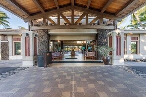 A covered entrance with stone walls, wooden benches, and a central planter. - Hilton Grand Vacations Club Kohala Suites Waikoloa (Waikoloa)