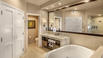 A modern bathroom with a freestanding bathtub, a vanity with a mirror, and a toilet.