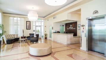 A hotel lobby with a reception desk, a sofa, a coffee table, and an elevator.