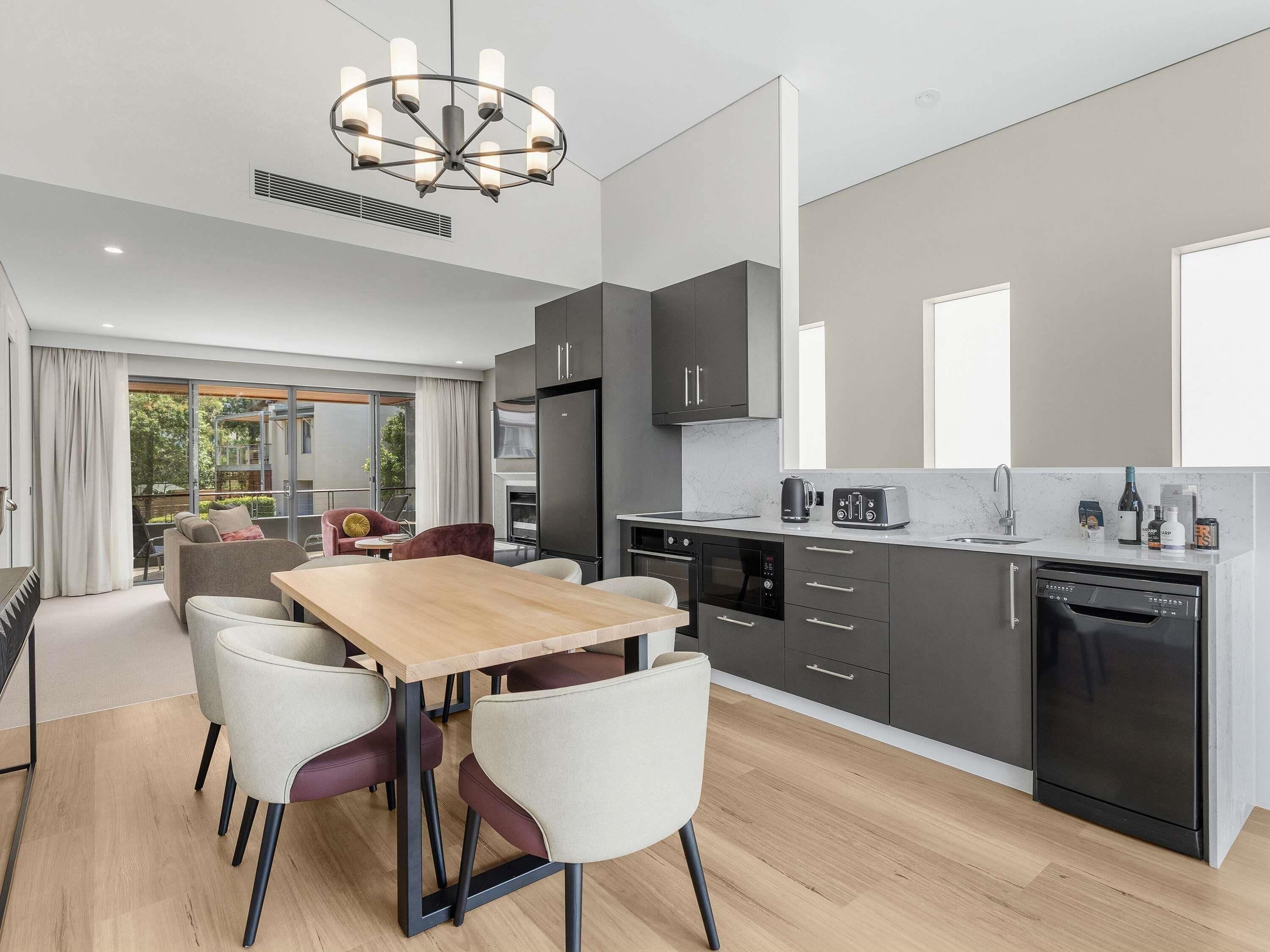 A modern kitchen with a dining area, a built-in oven, and a dishwasher.