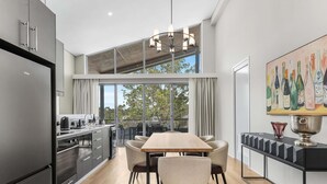 Une cuisine moderne avec un coin repas, de grandes fenêtres et une mezzanine.