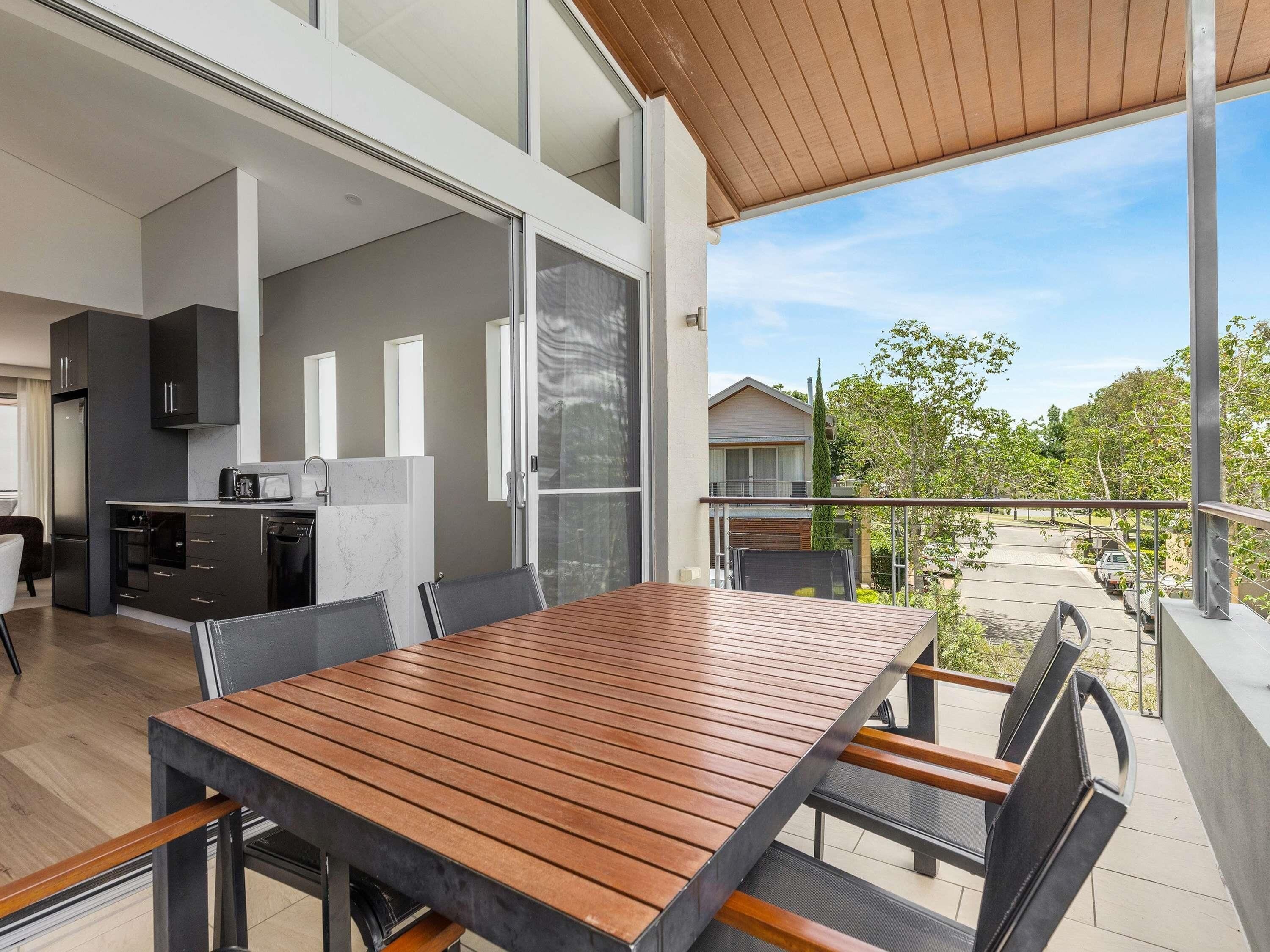 A modern kitchen with a dining area, large windows, and a view of the neighborhood.