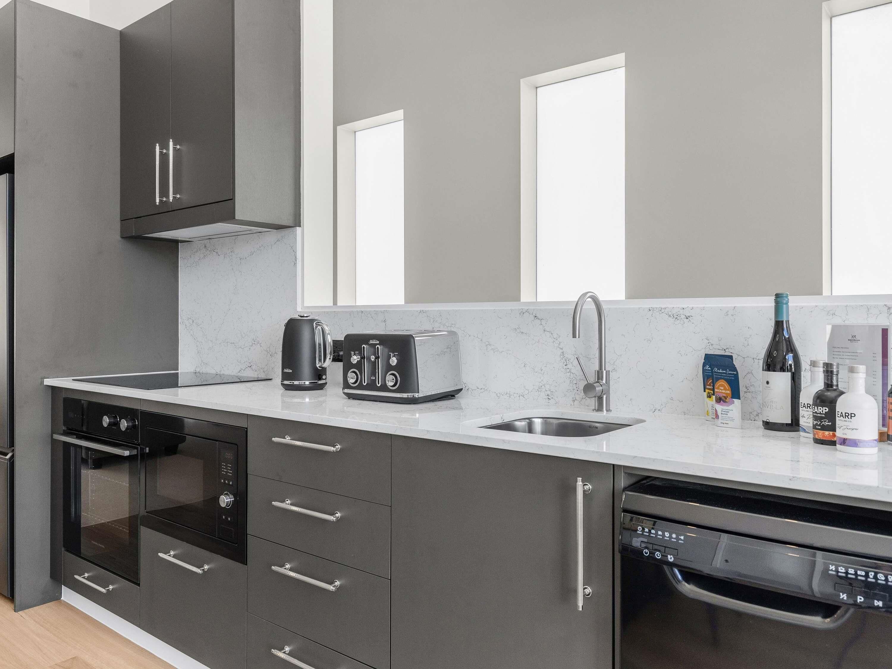 A modern kitchen with a built-in dishwasher, a coffee maker, and a wine bottle on the counter.