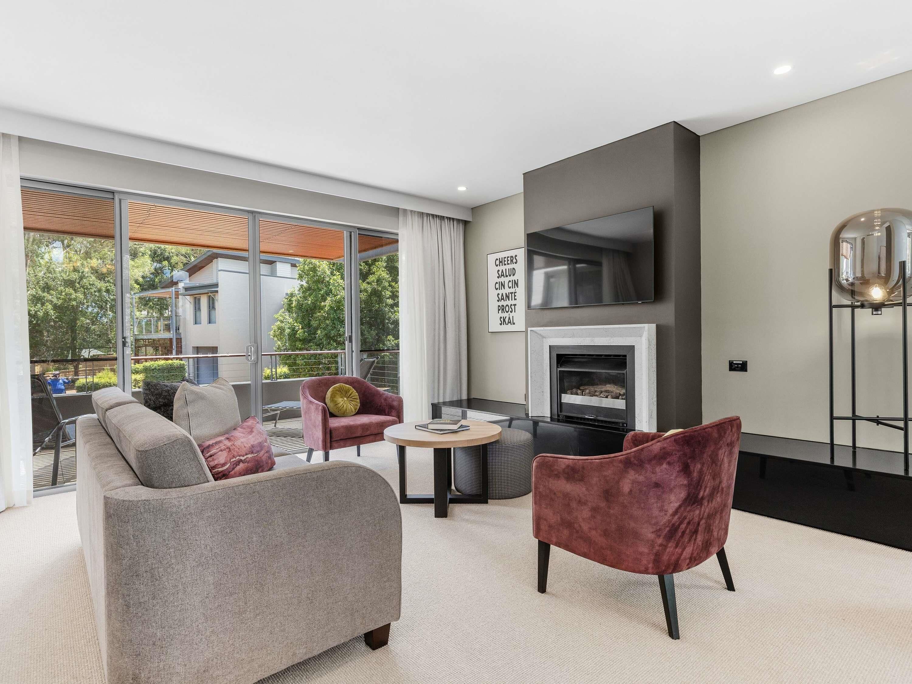 Una sala de estar moderna con un sofá, sillones, chimenea y televisión.