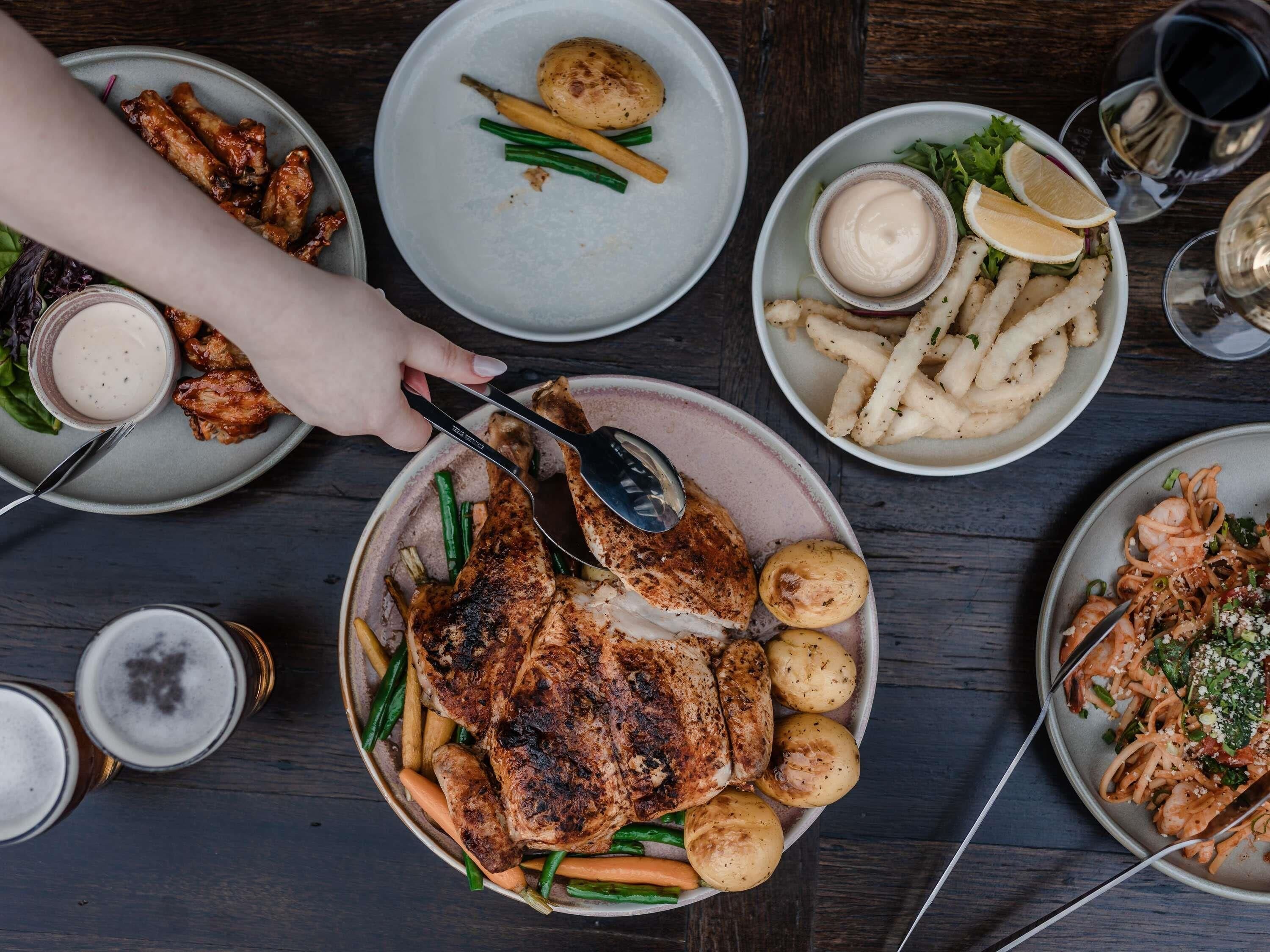 A table with various dishes including grilled chicken, vegetables, and seafood.