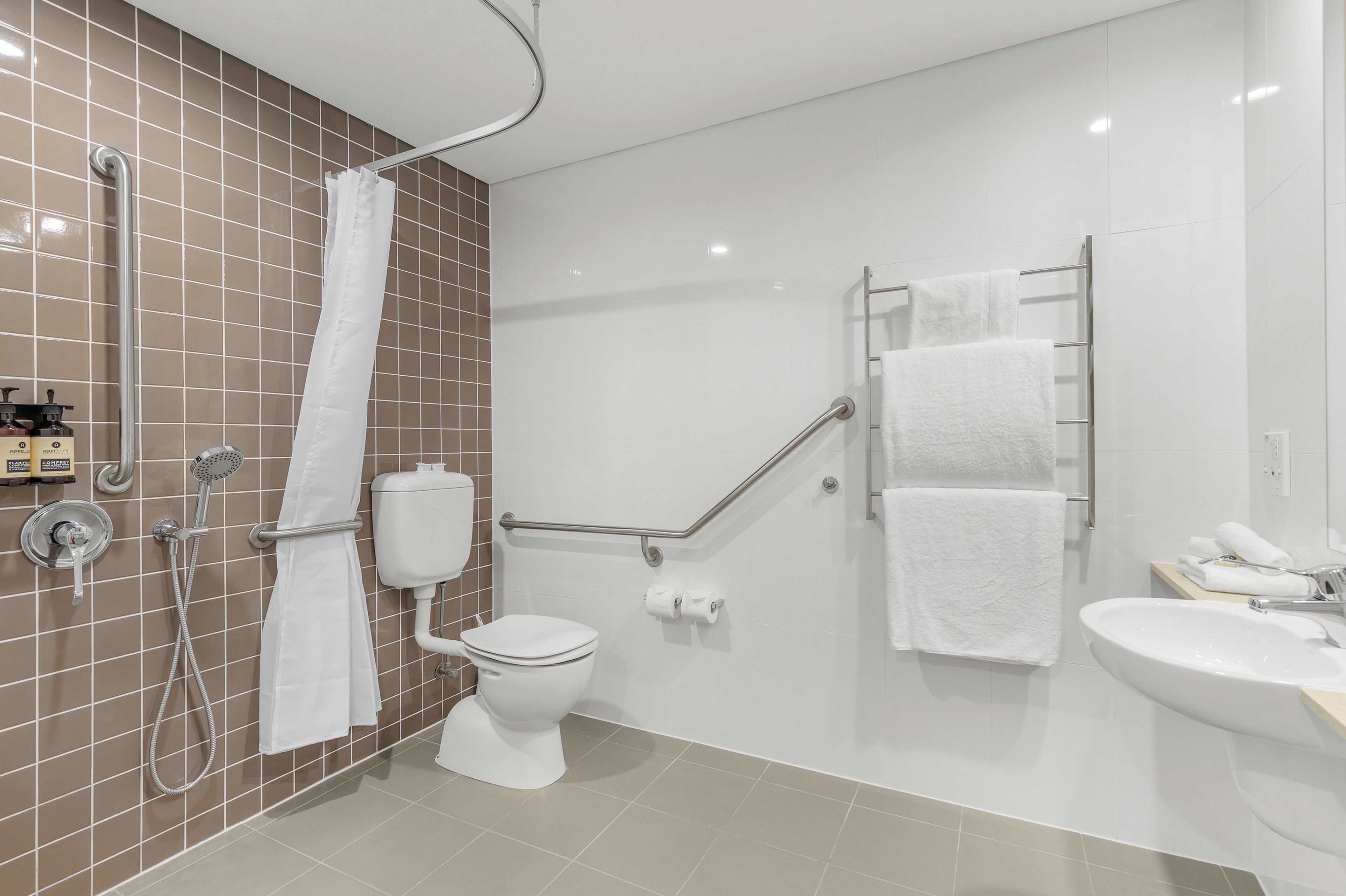 A modern bathroom with a shower, toilet, and sink.