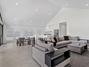 A modern living room with a sofa, coffee table, and dining area. - Peppers Hunter Valley (Pokolbin)
