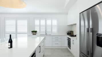 Una cocina moderna con armarios blancos, una isla grande, electrodomésticos de acero inoxidable y una lámpara colgante.