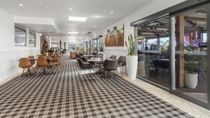 Un hall d’hôtel avec un tapis à carreaux, des meubles modernes et de grandes fenêtres.