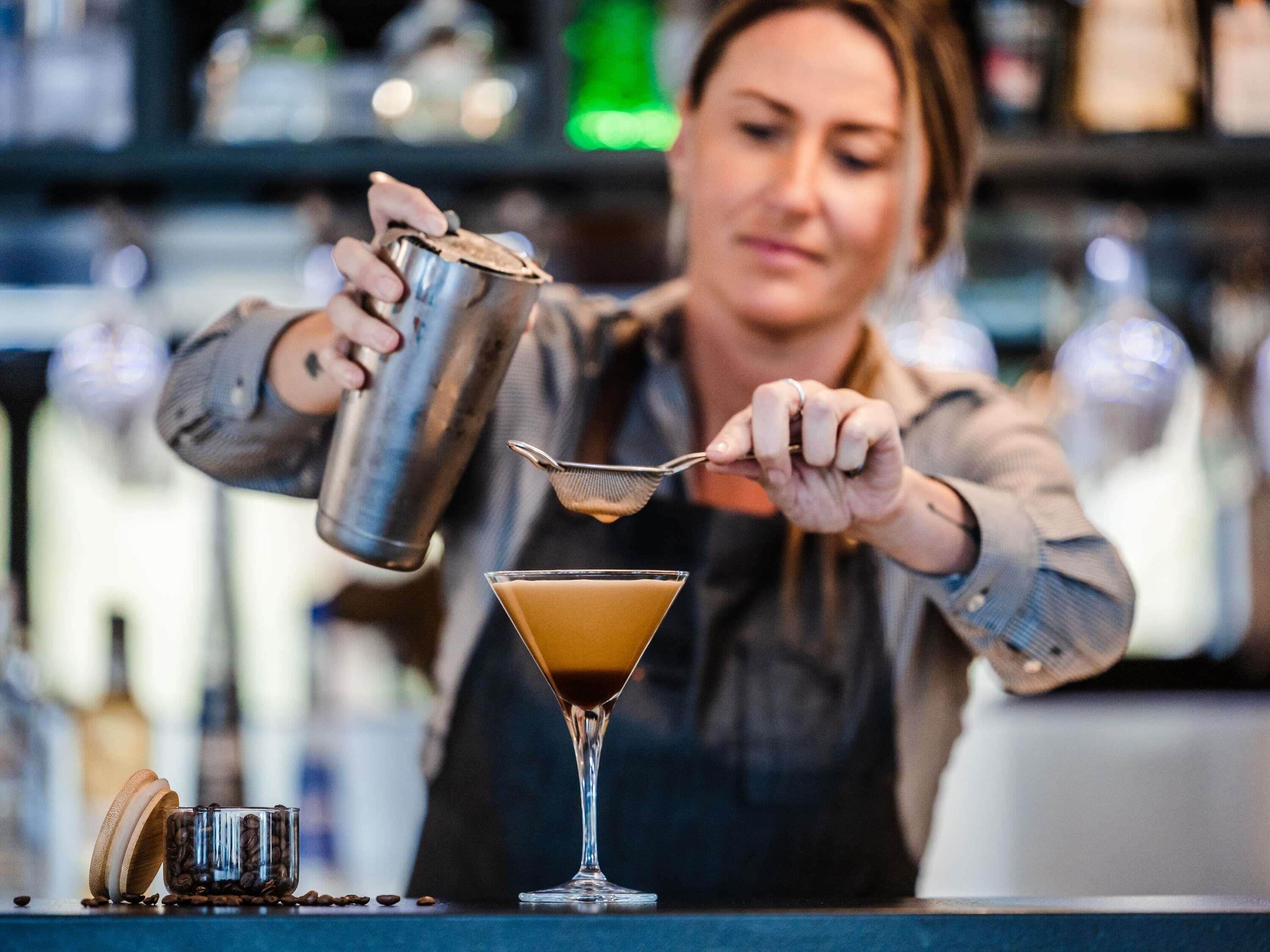 Una persona sirviendo una bebida en una copa de martini.