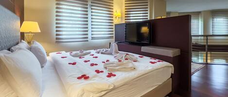 Habitación de hotel con una cama grande, televisión y balcón.