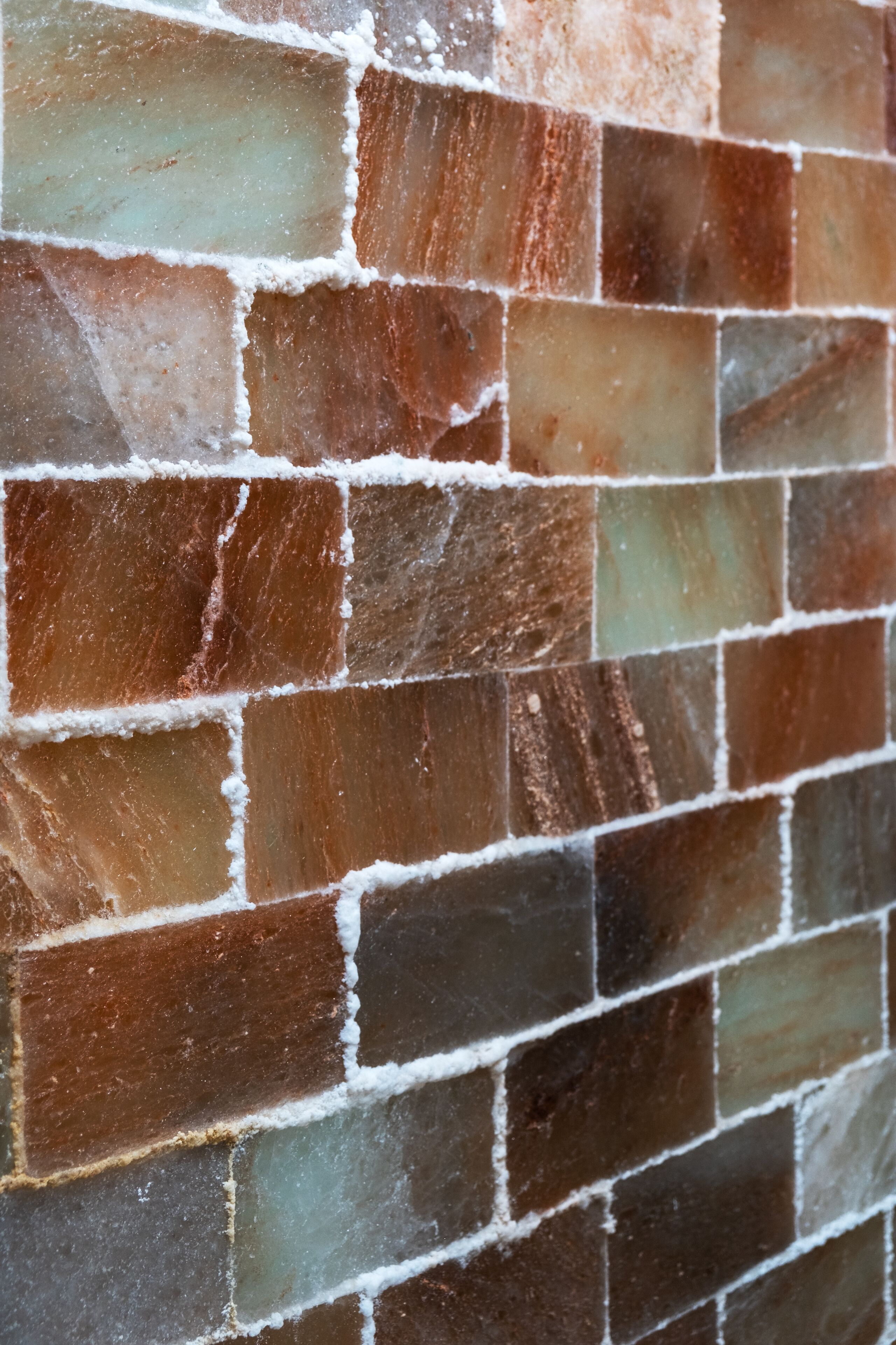 A close-up of a mosaic tile wall with various shades of brown and green tiles.