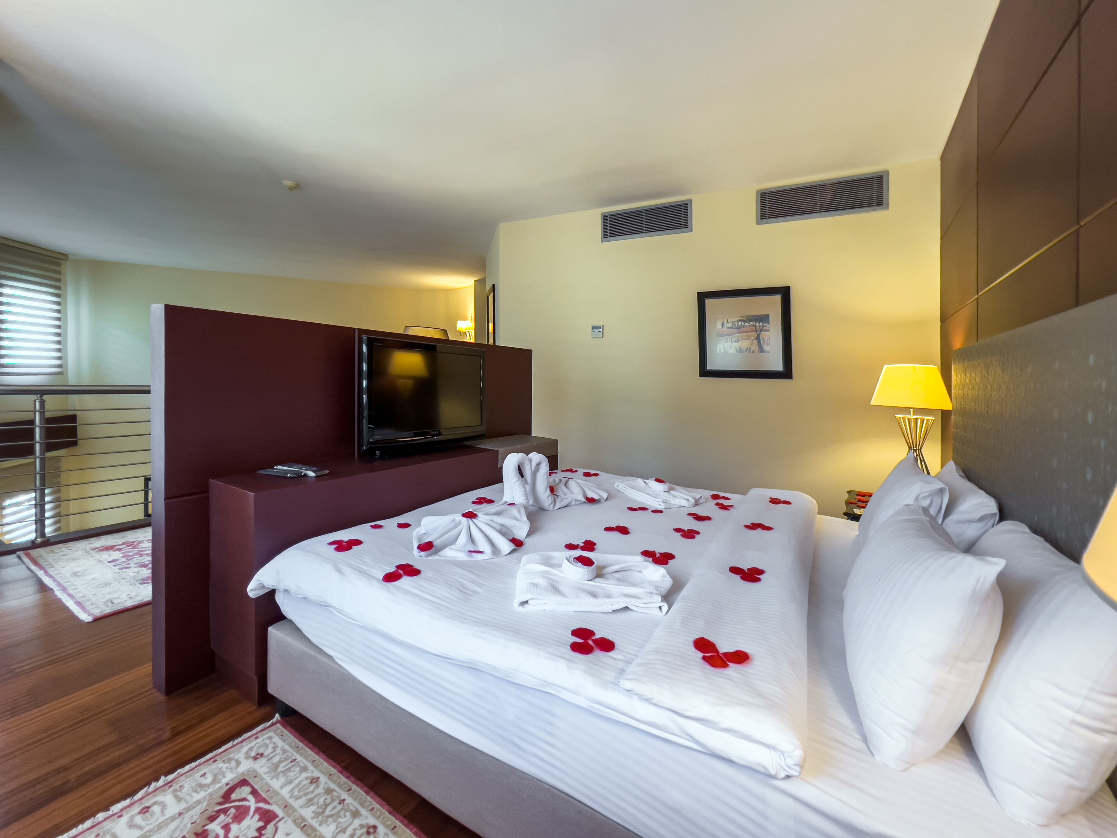 A hotel room with a bed, a TV, a desk, and a lamp.