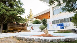 Un espace spa comprenant un jacuzzi, un mur en pierre et un bâtiment à l’architecture moderne, doté d’une signalétique.