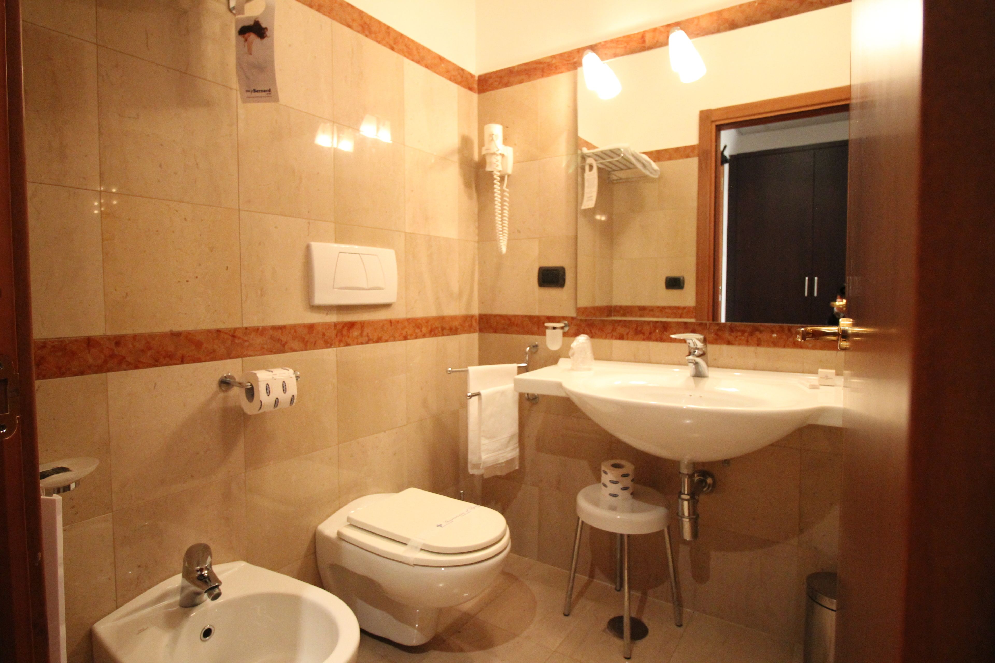 Un baño con inodoro, bidé, lavamanos y espejo.