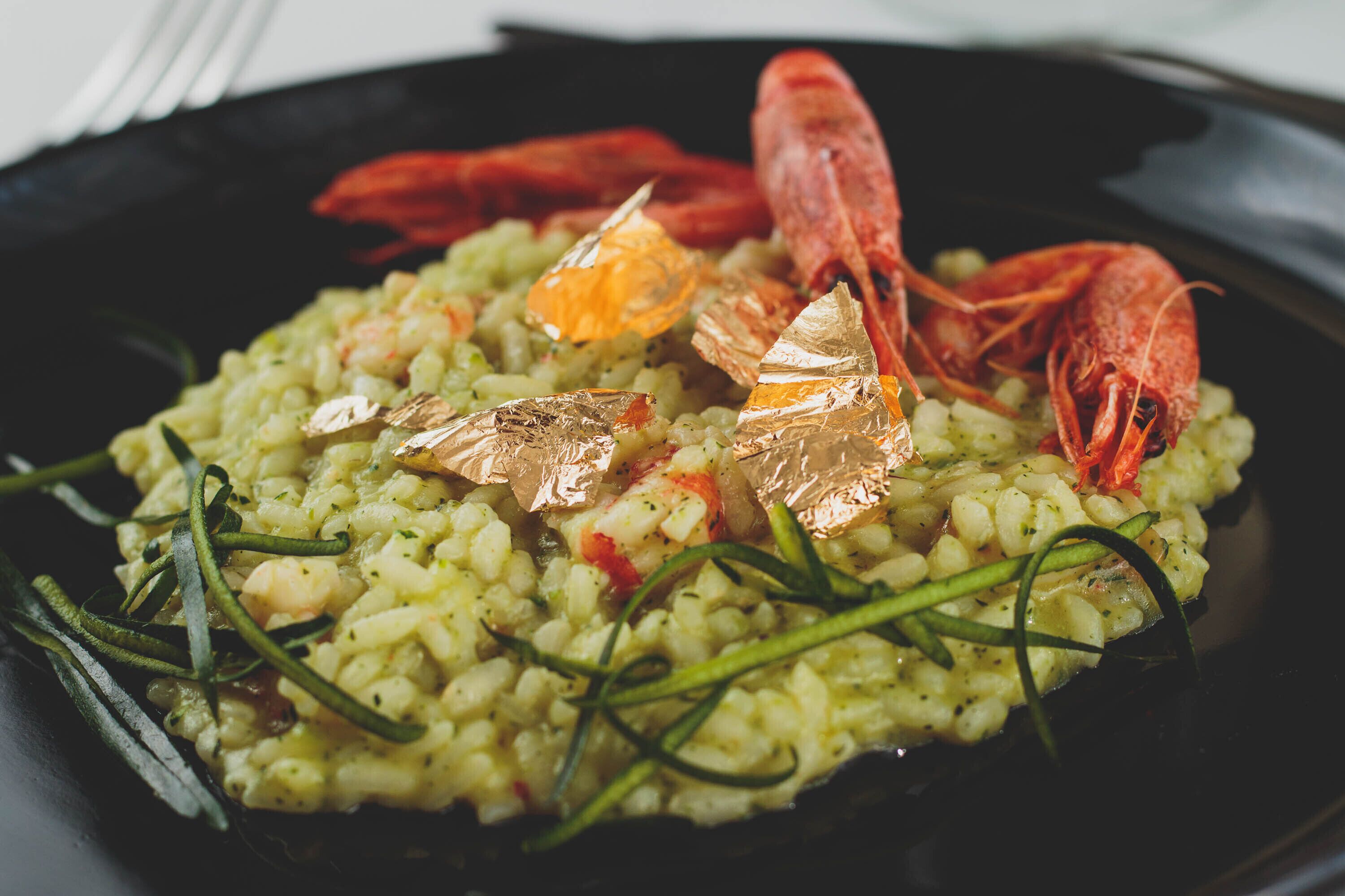 Een bord risotto met garnalen en garnering.