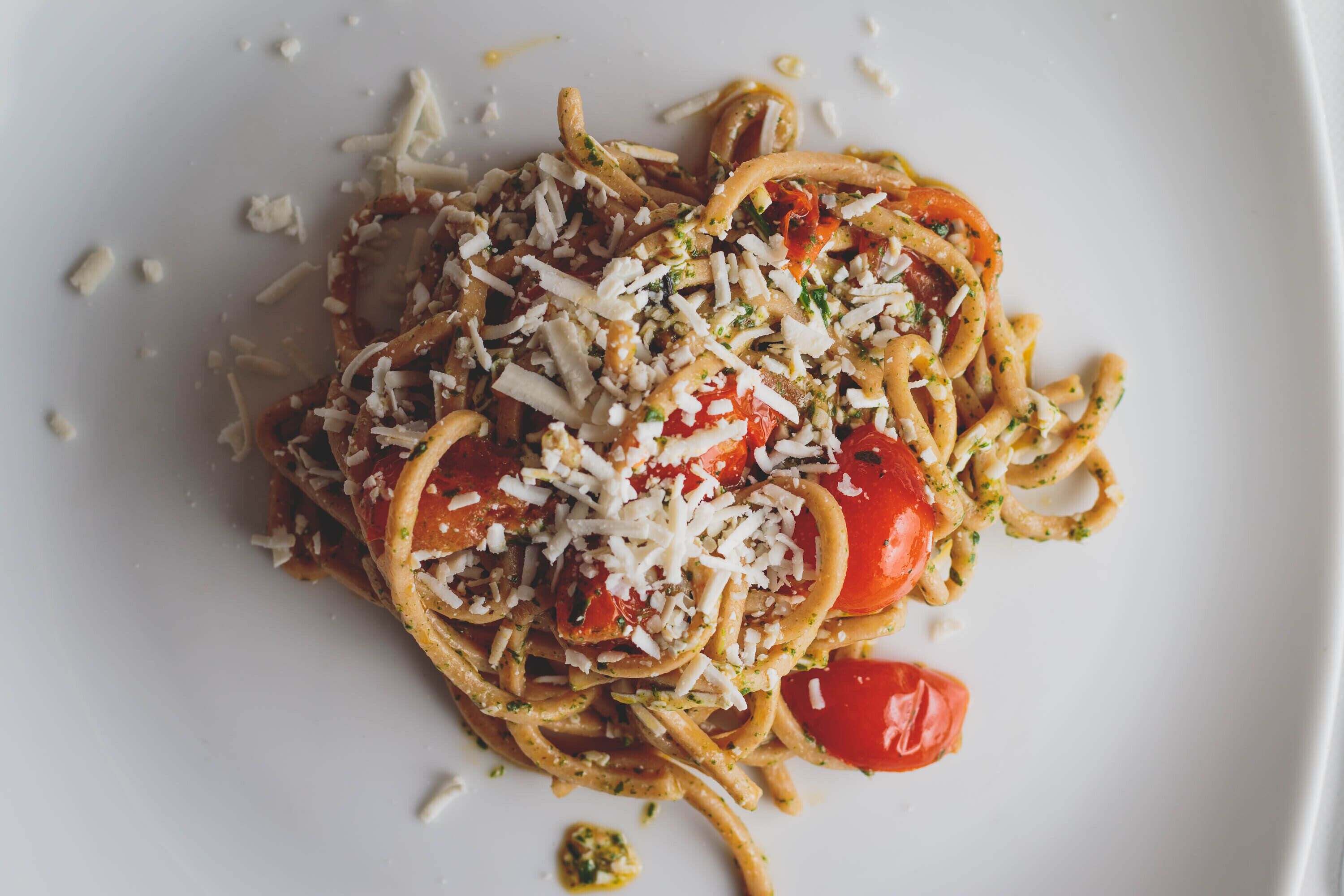 Un plato de espagueti con tomates cherry y queso rallado.