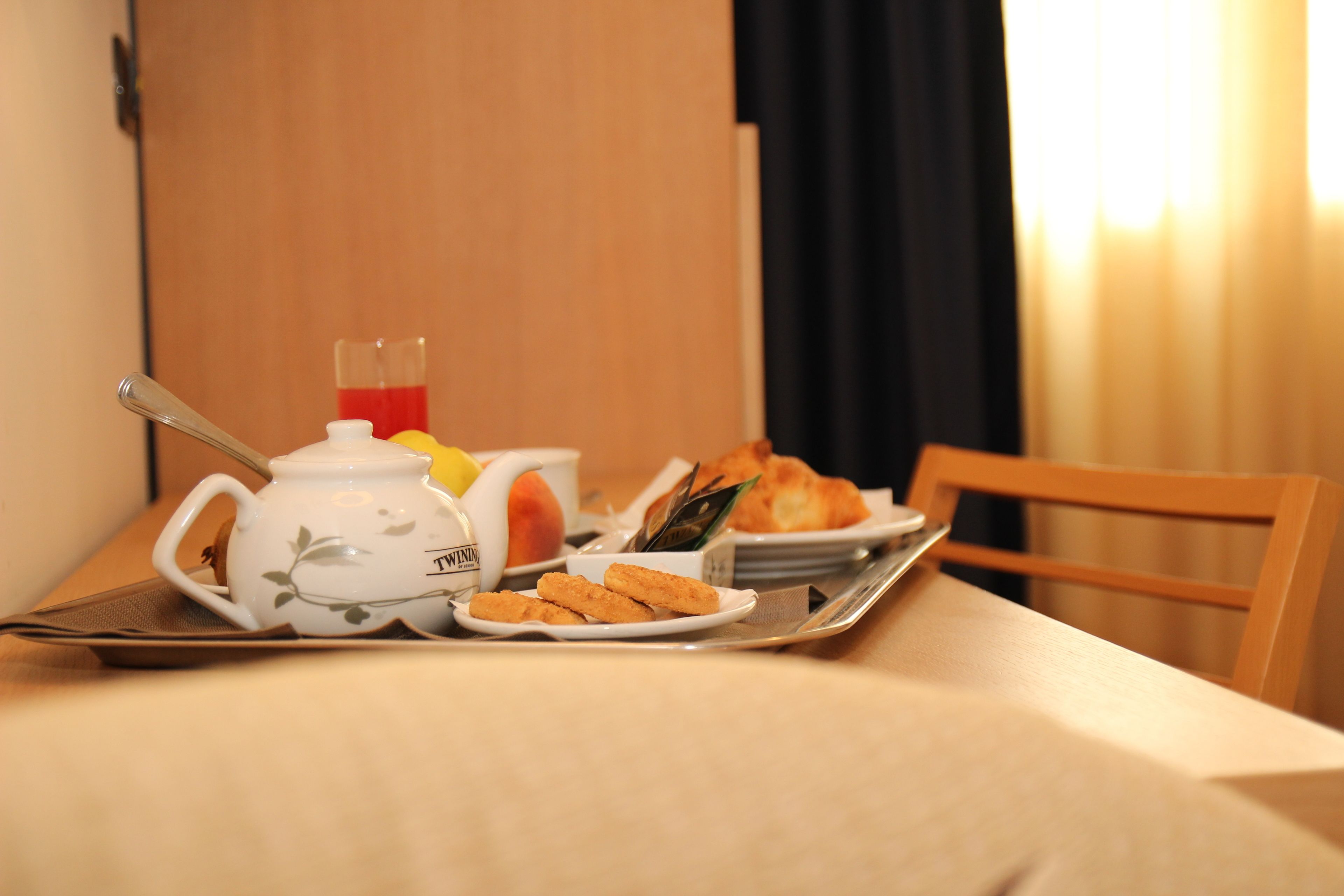 Un plateau de petit-déjeuner avec une théière, des tasses, un croissant et des biscuits, posé sur une table.