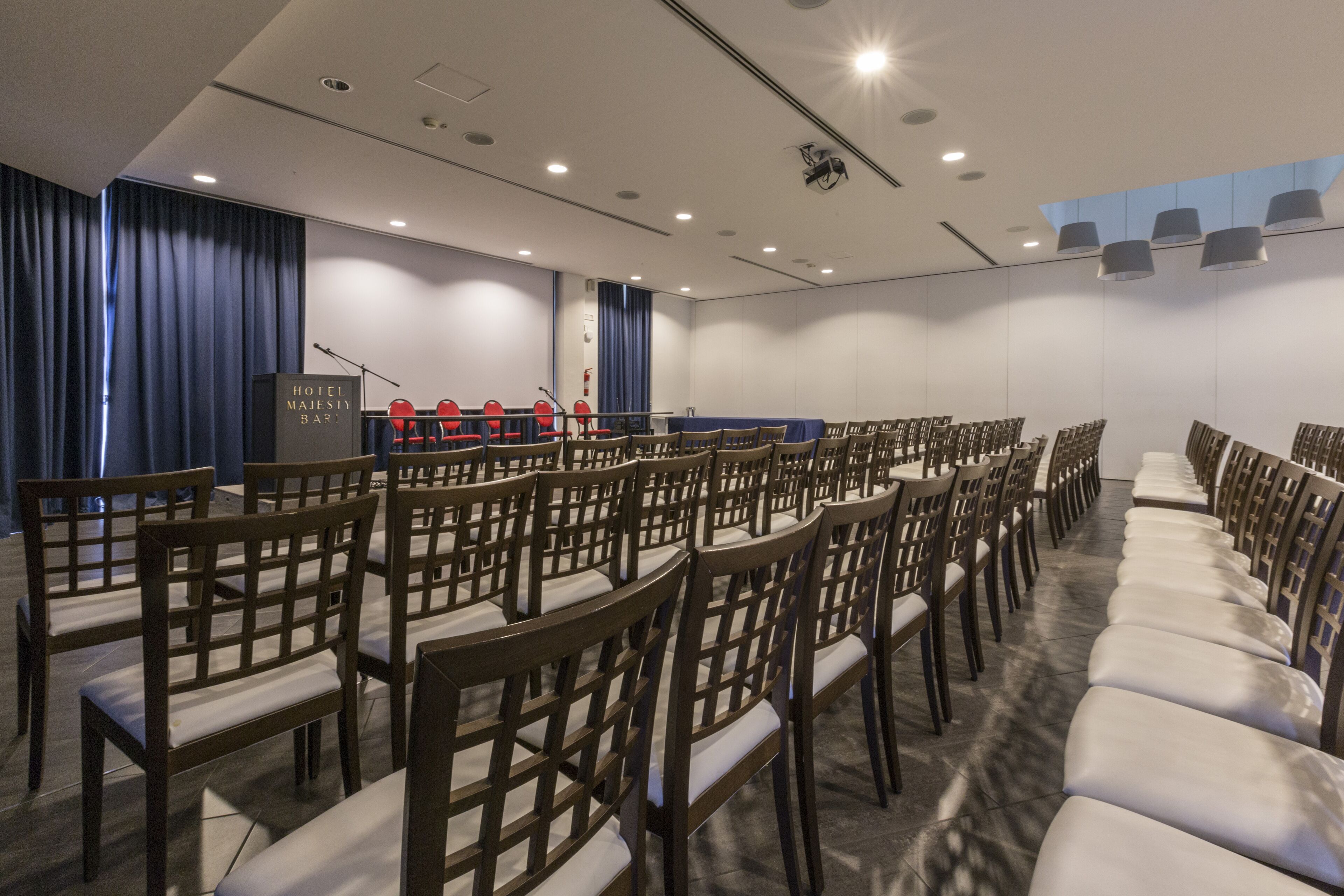A conference room with rows of wooden chairs and a podium at the front.