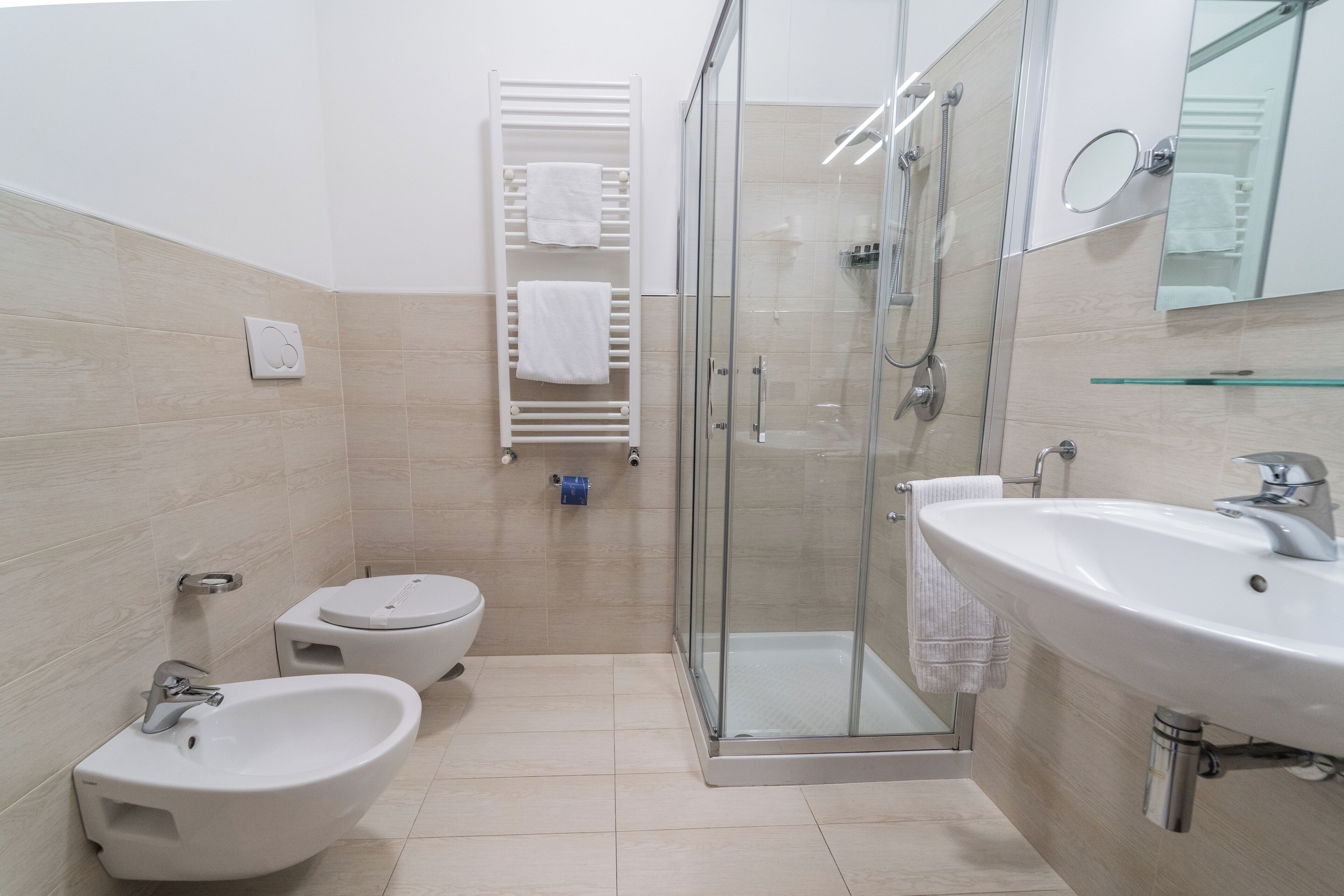 A modern bathroom with a bidet, a glass-enclosed shower, and a large sink.