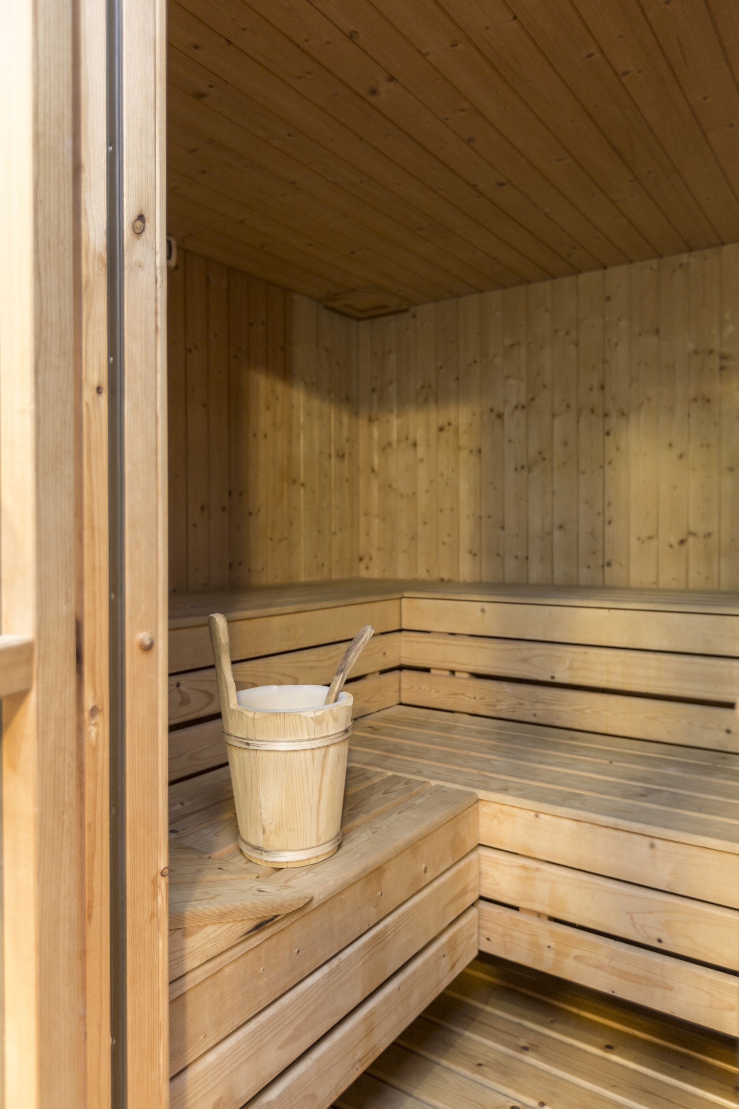 Una sauna de madera con bancos y un cubo.