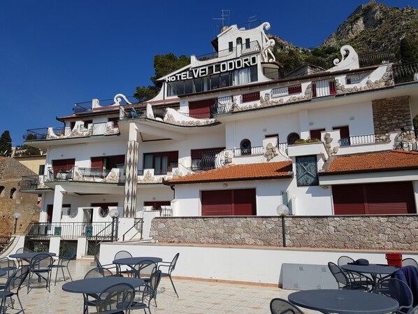 A hotel with a white facade, red shutters, and balconies with metal railings. - Hotel Vello d'Oro (Taormina)