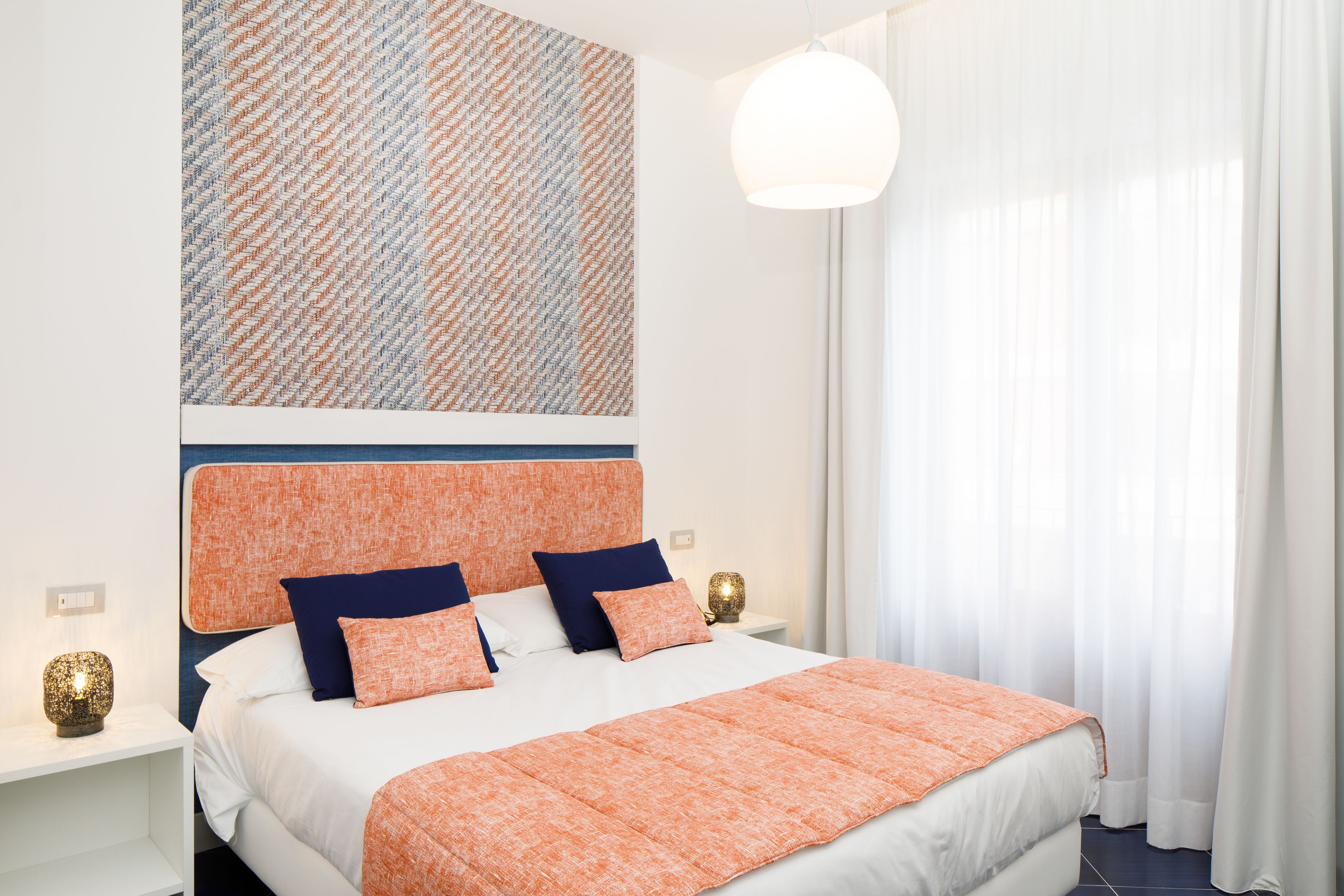 Habitación de hotel ordenada con una cama grande, una mesita de noche con lámpara y una obra de arte colgada en la pared.