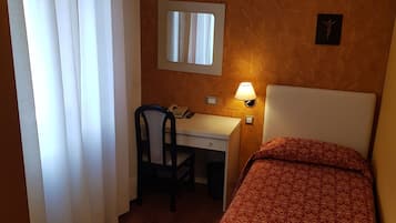 Ein Hotelzimmer mit einem Bett, einem Schreibtisch, einem Stuhl, einer Lampe und einer Klimaanlage.