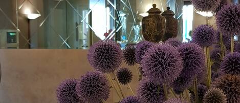 Un jarrón blanco con flores moradas sobre una mesa de madera.
