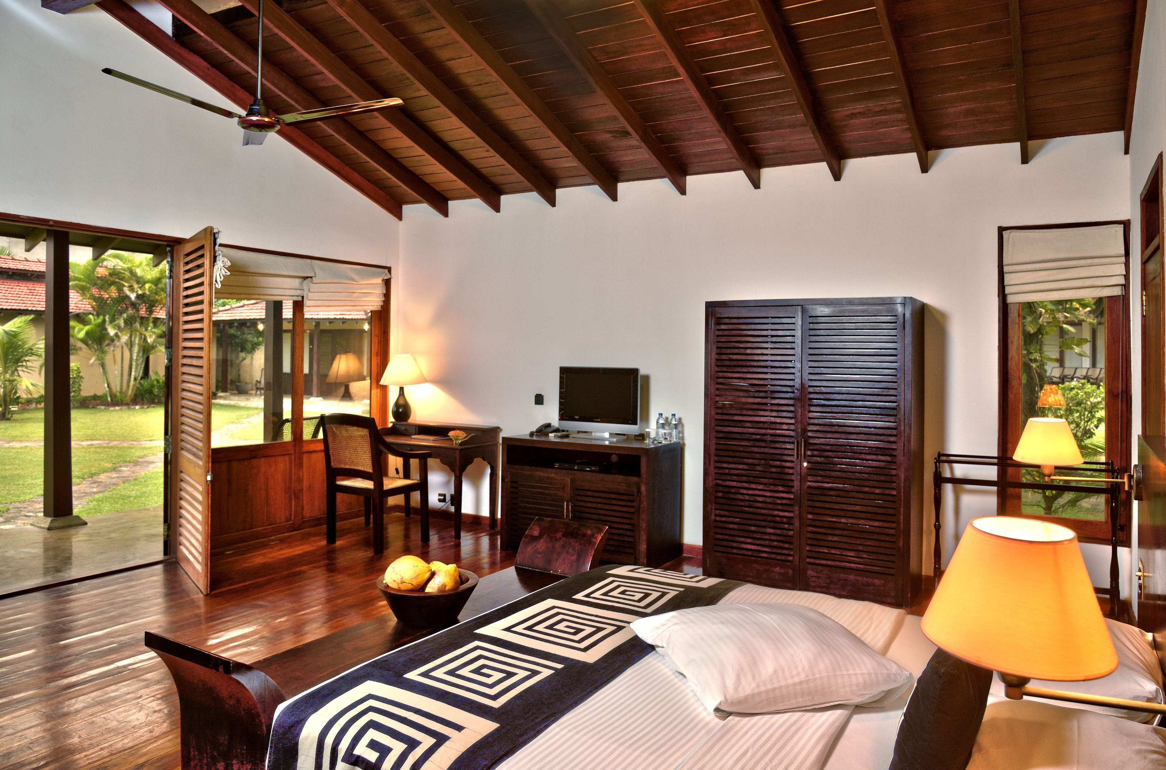 A bedroom with a bed, a desk, a television, and a wardrobe.