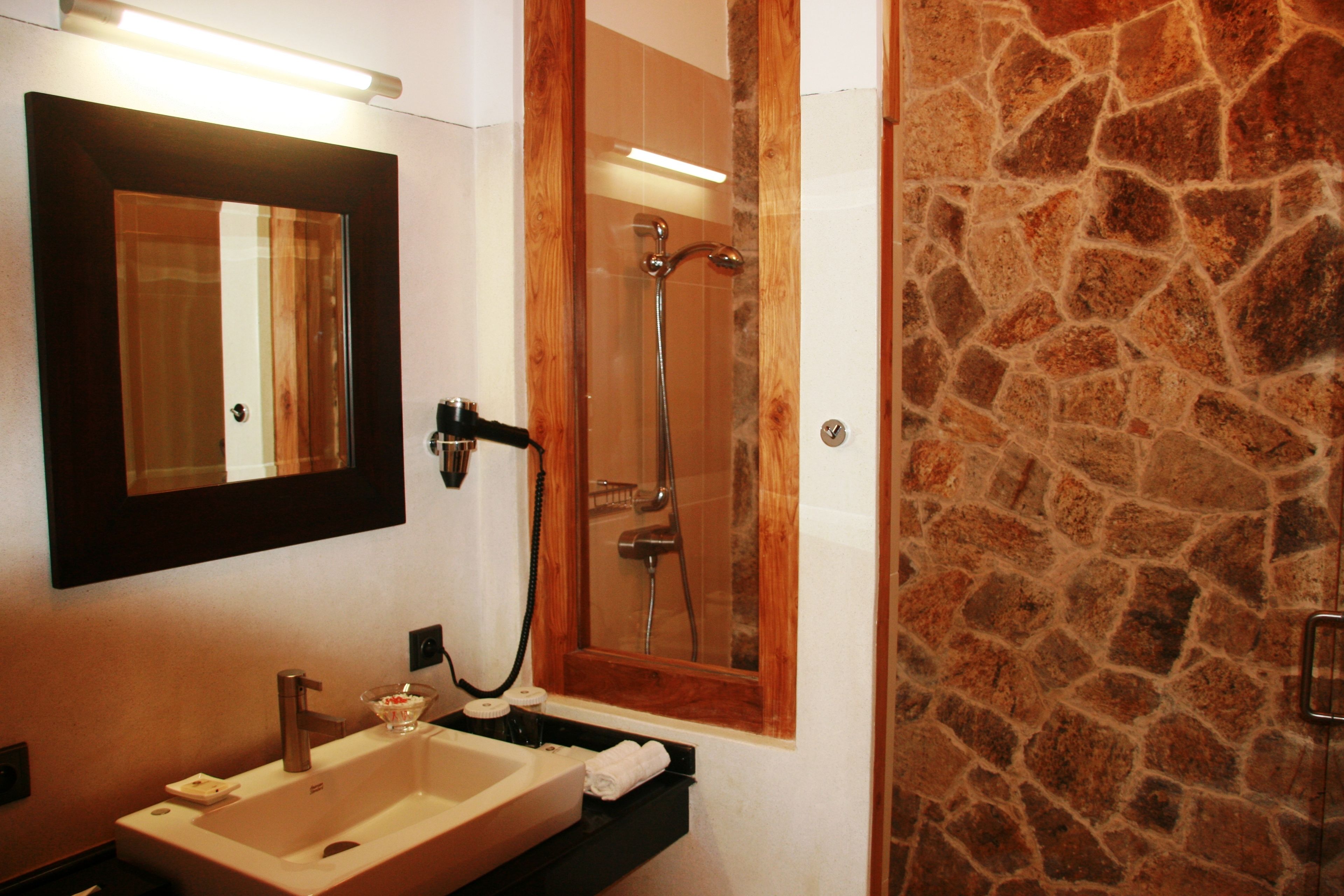 A bathroom with a large mirror, a sink, and a shower.