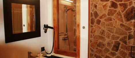 A bathroom with a large mirror, a sink, and a shower.