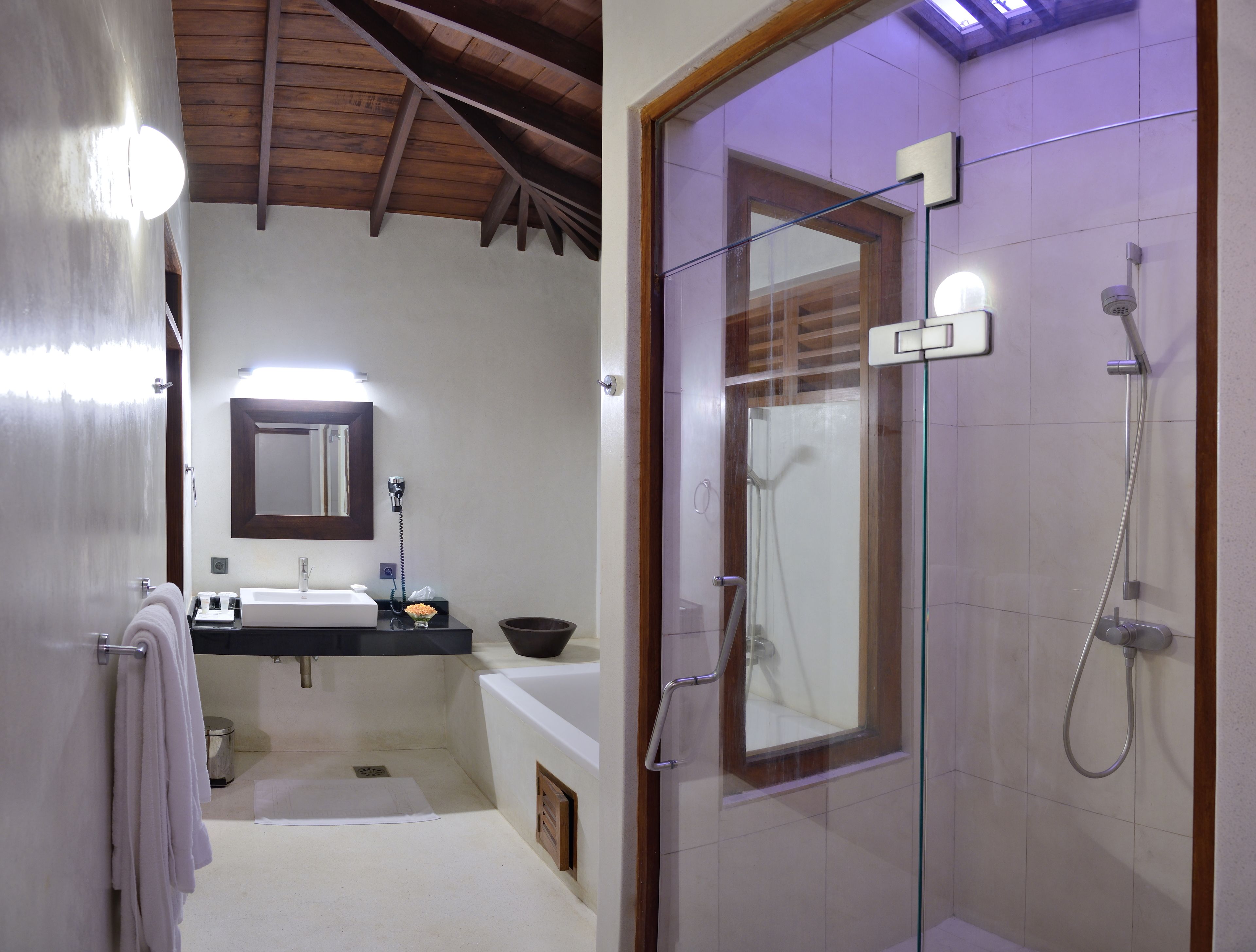 A bathroom with a shower, a sink, a mirror, and a towel rack.
