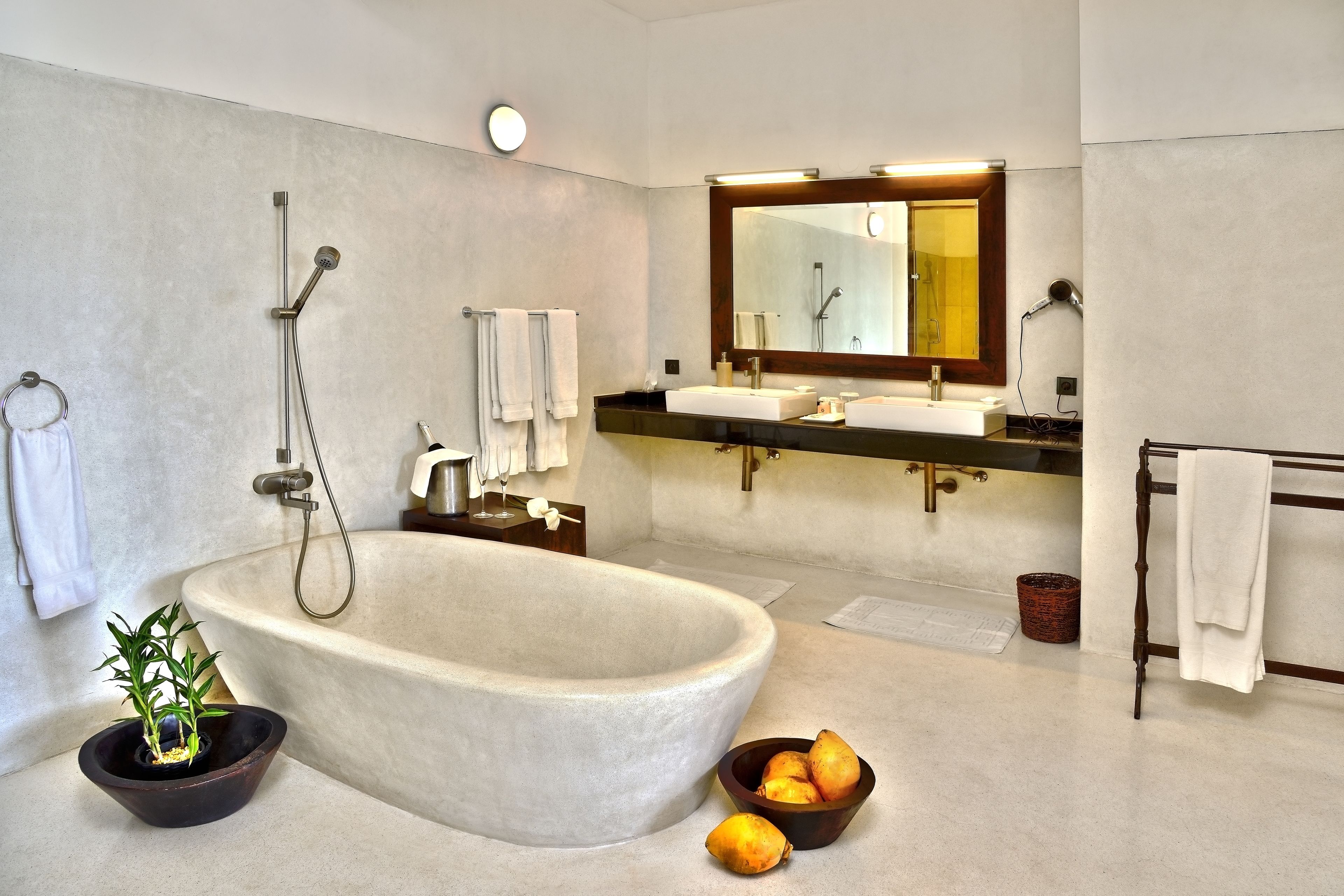 A modern bathroom with a freestanding bathtub, two sinks, a large mirror, and a towel rack.