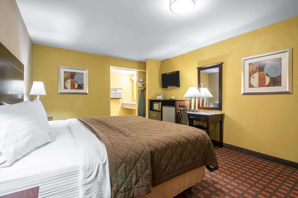 Habitación de hotel con cama, escritorio, silla y obras de arte en las paredes.