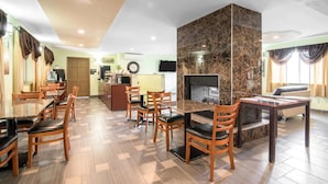 A dining area with wooden chairs and a marble fireplace.