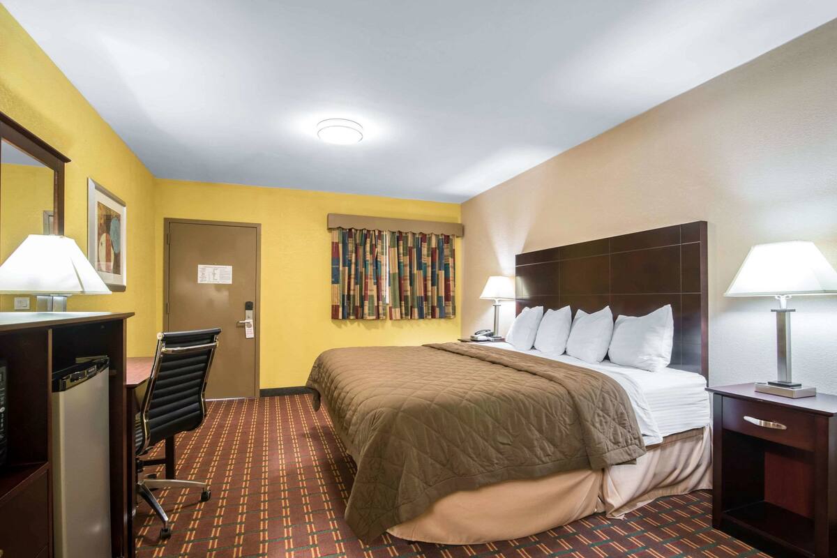 Una habitación de hotel con cama, escritorio, silla y puerta.