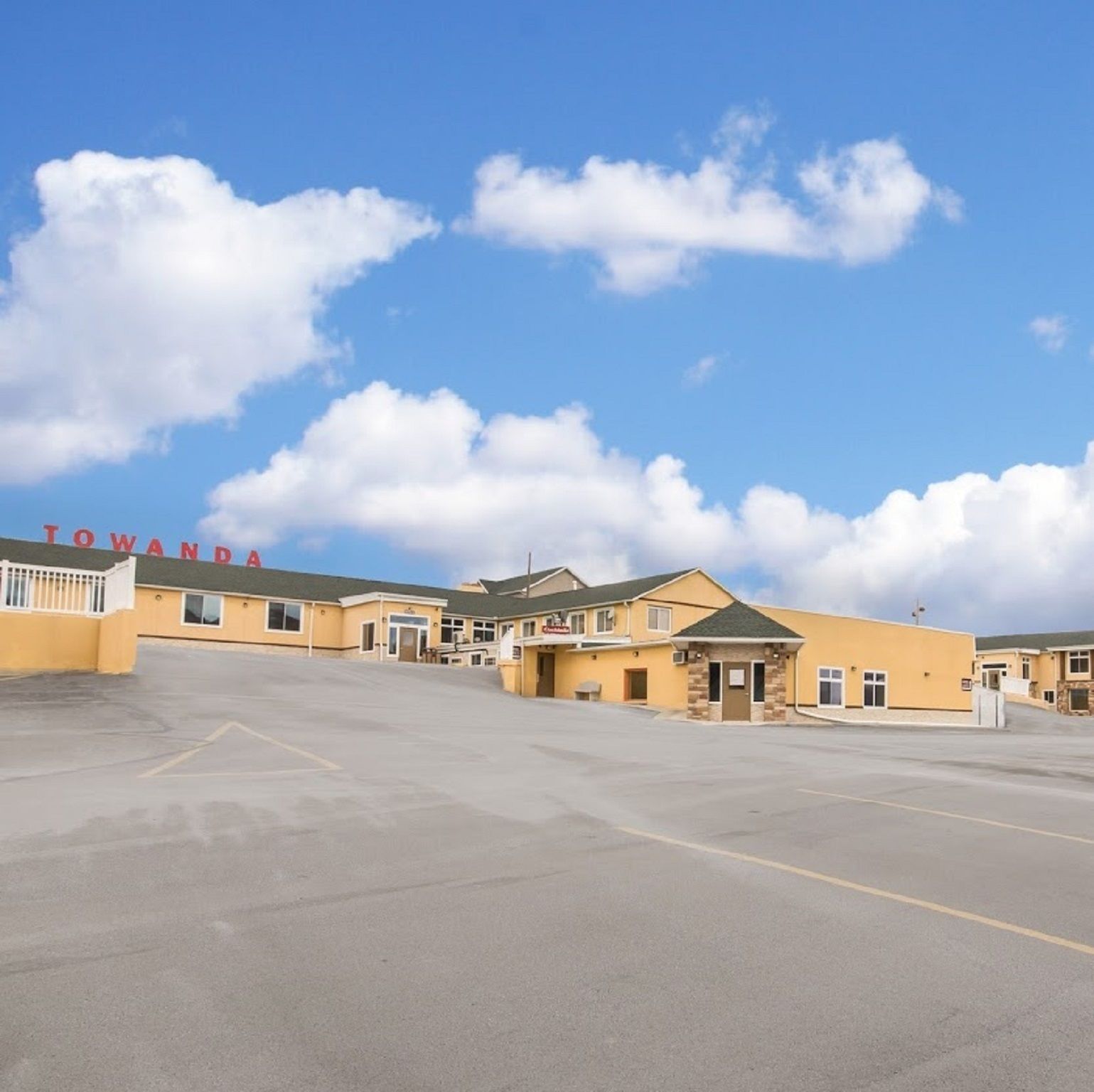 A parking lot with a row of yellow buildings, one with 'Towanda' written on it.